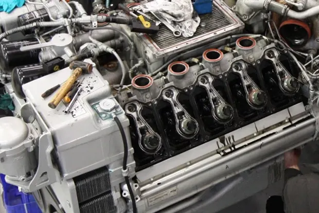 Diesel engine undergoing repair with visible pistons and tools on top.